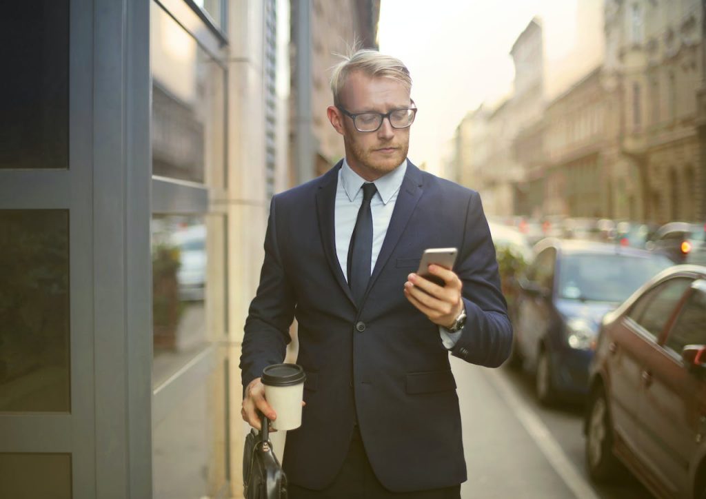 person-walking-looking-his-phone-successful-businessman