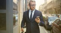 person-walking-looking-his-phone-successful-businessman