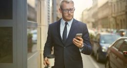 person-walking-looking-his-phone-successful-businessman