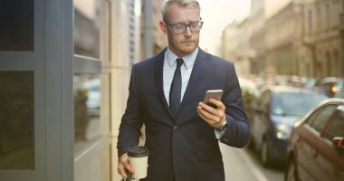 person-walking-looking-his-phone-successful-businessman