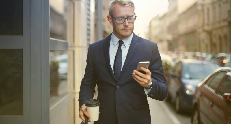 person-walking-looking-his-phone-successful-businessman