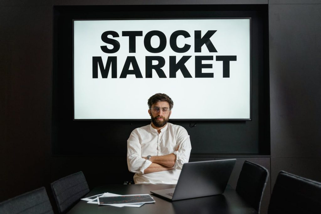 man-sitting-behind-stock-market-banner